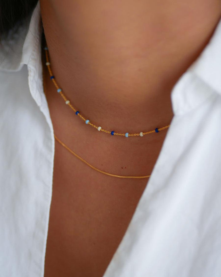 enamel Lola-Halskette Marine N55g am Hals abgebildet, Goldkette mit kleinen blauen und weißen Perlen. Modell n55g-marine-n55g-marine-2