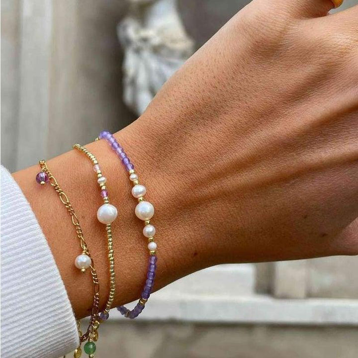 Hultquist Copenhagen Das Maya-Armband mit lila Perlen und goldenen Details wird am Handgelenk getragen. Modell S08105G