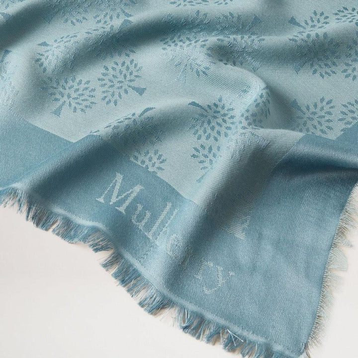 Mulberry Tree Square Silk Organic Cotton Cloud zeigt einen blauen Schal mit dezentem Baummuster. Modell vs4639709d140