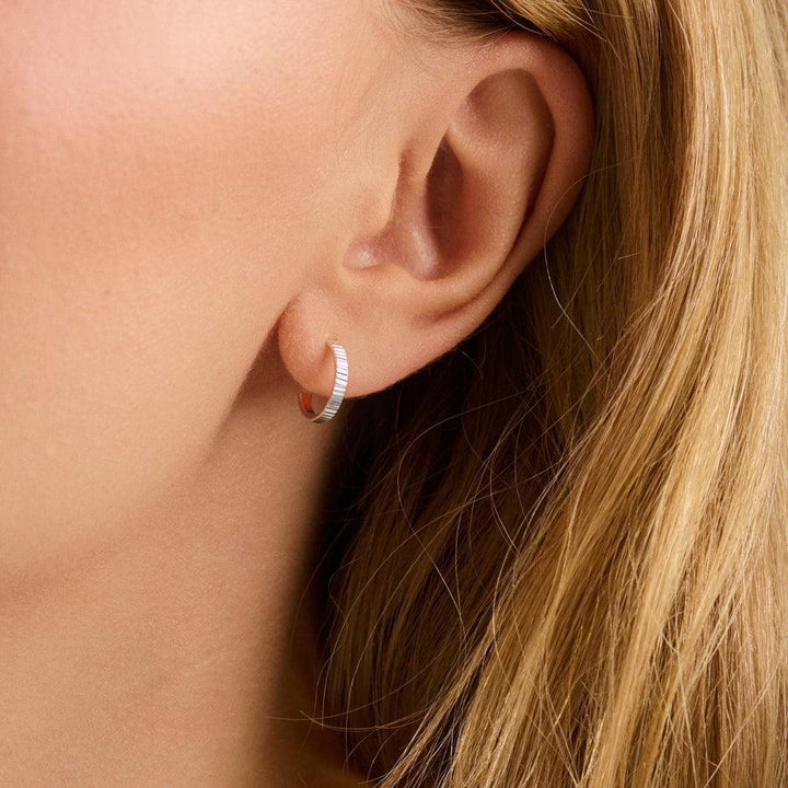 Pernille Corydon Sea Reflection Mini Hoops im Ohr abgebildet, silberne Kreole mit geriffelter Oberfläche. Modell E-483-S