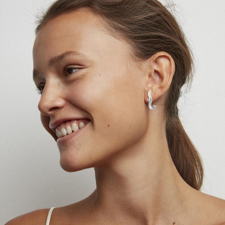 Der silberne Ohrring „The Darning Needle“ von Polar Jewelry wird vom Model getragen, von der Seite dargestellt. Modell st-l-sl-wz-00335-2.