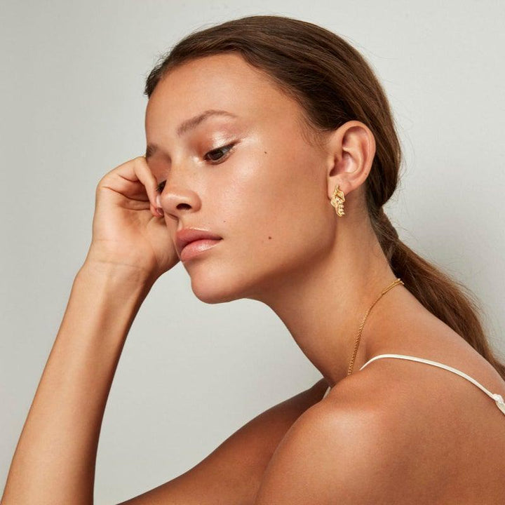 Der vom Model getragene Ohrring „Prinzessin auf der Erbse“ in Goldton, elegant und modern. Modell pri-st-gd-wz-00310-2